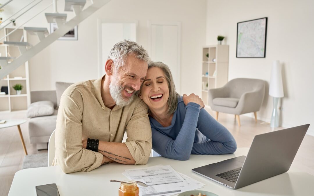 senior couple smiling while looking at laptop